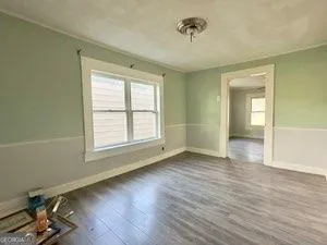 a view of an empty room with a window and wooden floor