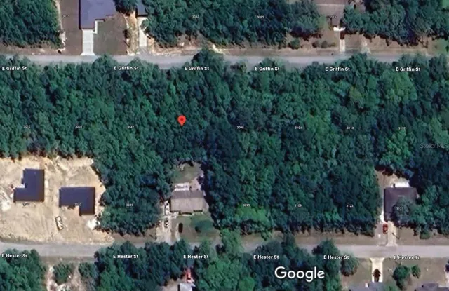 an aerial view of residential house with outdoor space and trees all around