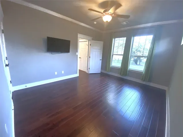 a view of an empty room with a window and wooden floor