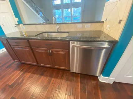 a close view of sink and washing machine with wooden floor