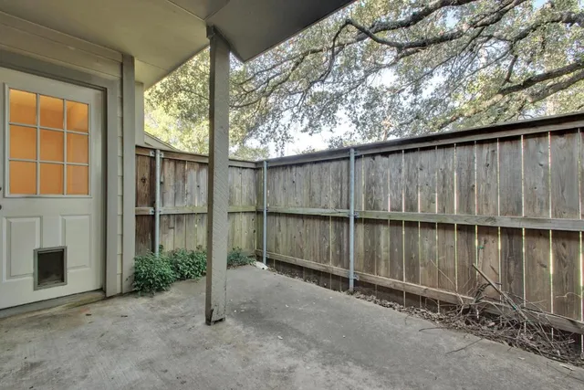 a backyard of a house with two plants and a table and chairs