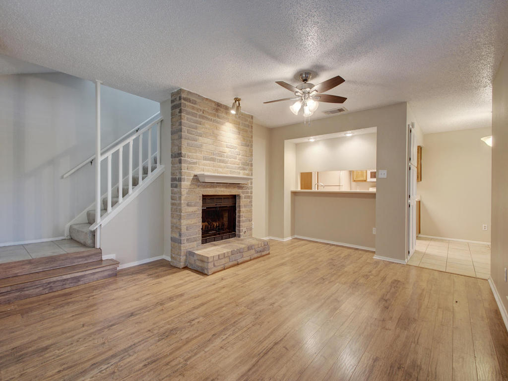 11301 Jollyville Road, Unit A3 Austin, TX 78759 - Photo 7 of 26 a view of an empty room with wooden floor a ceiling fan and a fireplace