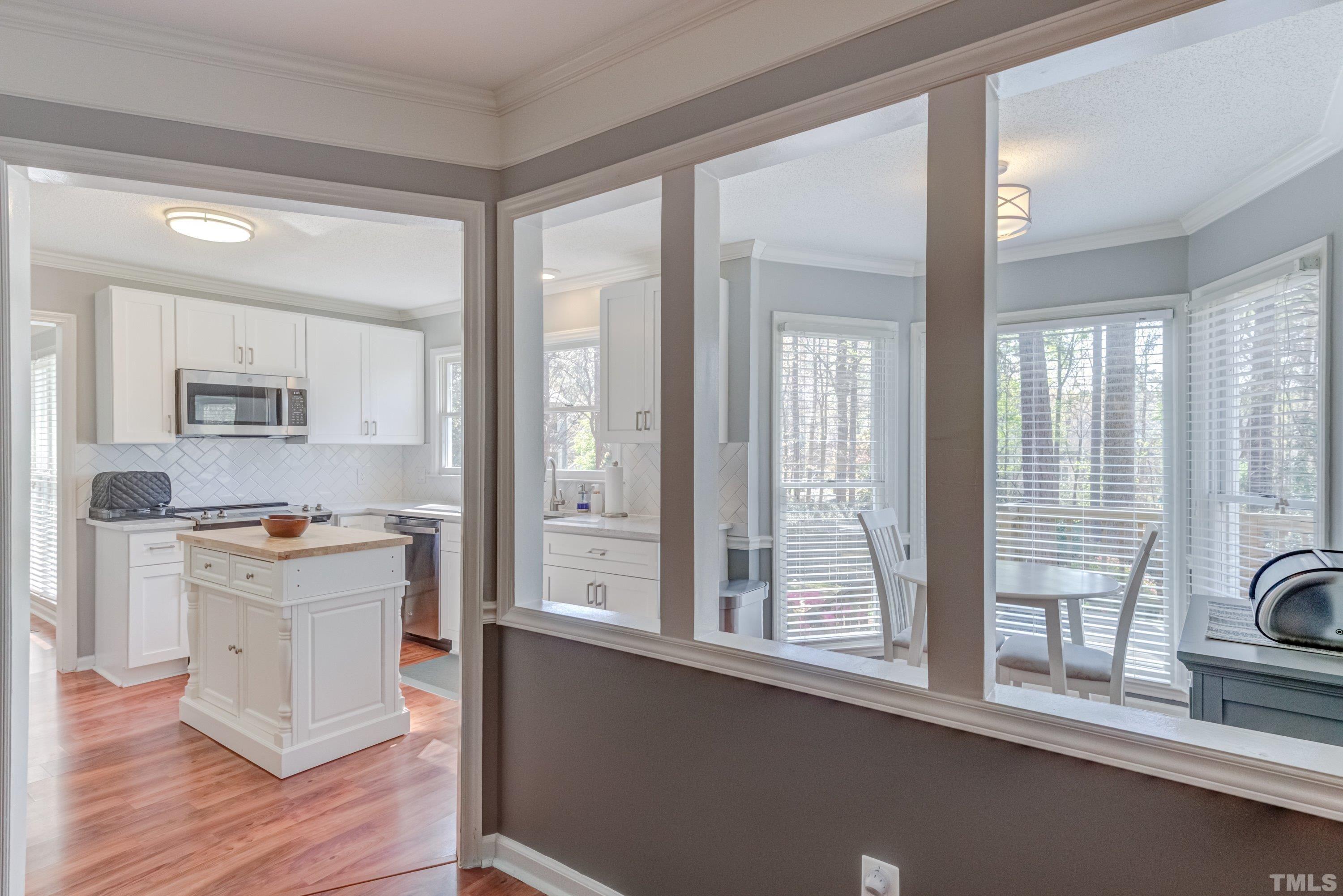 105 McIntire Lane Cary, NC 27513 - Photo 11 of 32 a kitchen with stainless steel appliances a stove a sink and white cabinets with wooden floor