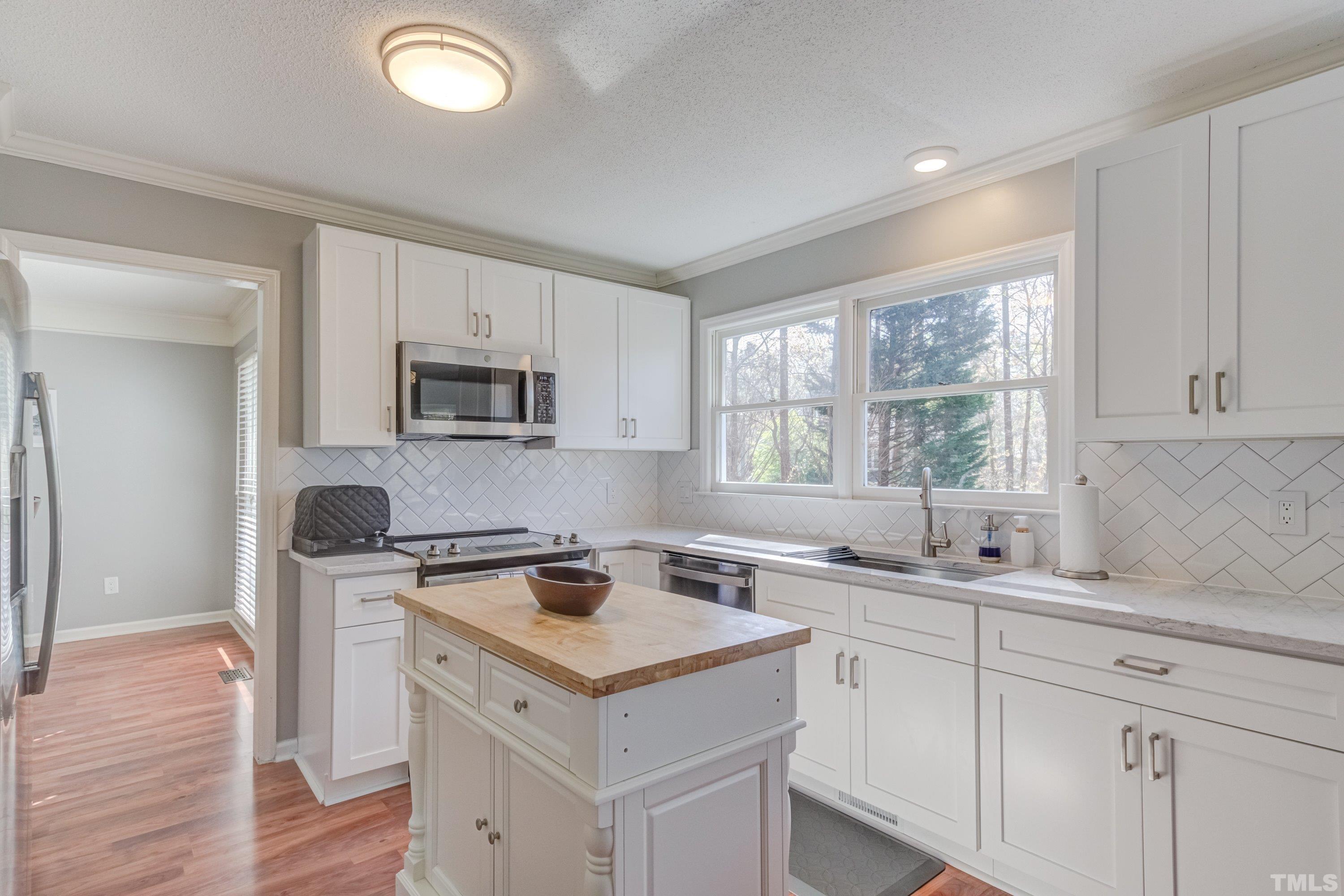 105 McIntire Lane Cary, NC 27513 - Photo 12 of 32 a kitchen with a sink a stove a microwave and wooden floor