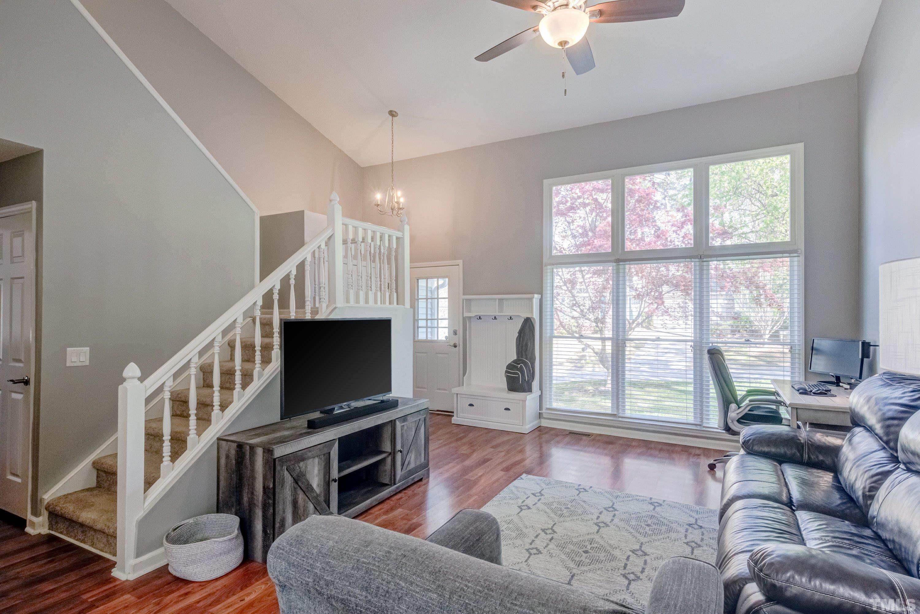 105 McIntire Lane Cary, NC 27513 - Photo 3 of 32 a living room with furniture a flat screen tv and a floor to ceiling window