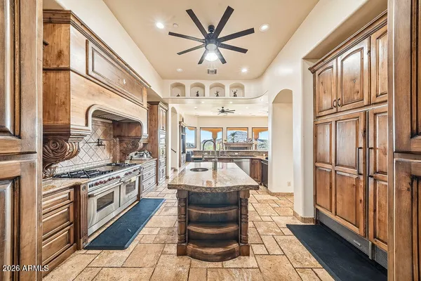 a kitchen with stainless steel appliances granite countertop a refrigerator a sink dishwasher a stove and a dining table with wooden floor