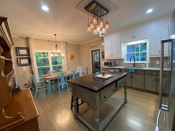 a kitchen with stainless steel appliances granite countertop a stove top oven a refrigerator a sink dishwasher a dining table and chairs with wooden floor