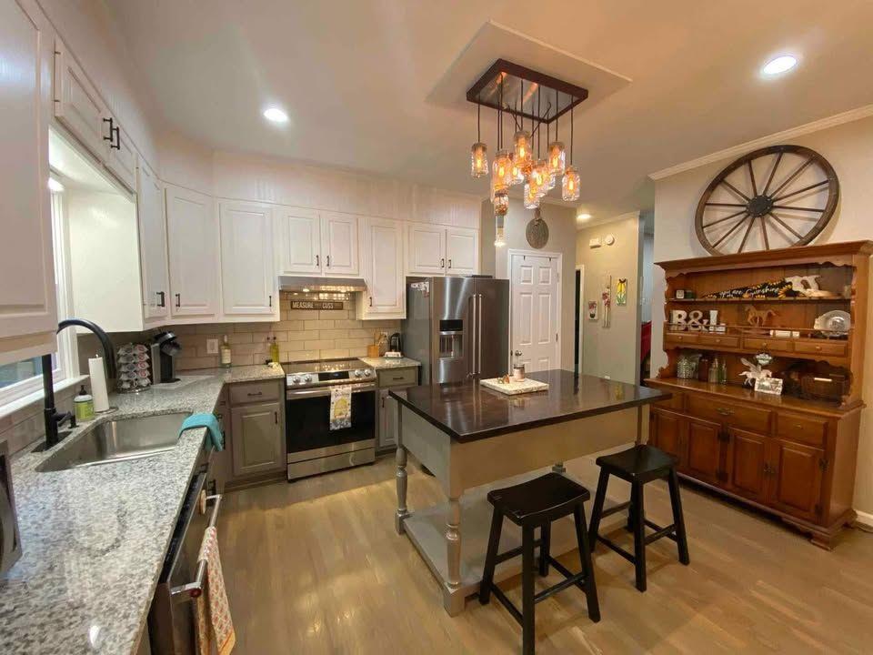 4005 South Apple Valley Road Commerce, GA 30529 - Photo 10 of 17 a kitchen with stainless steel appliances granite countertop a stove top oven a refrigerator a sink dishwasher a dining table and chairs with wooden floor
