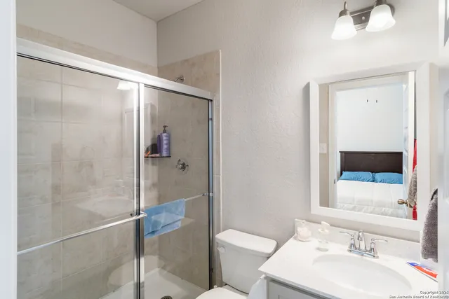 a bathroom with a shower sink vanity mirror and toilet