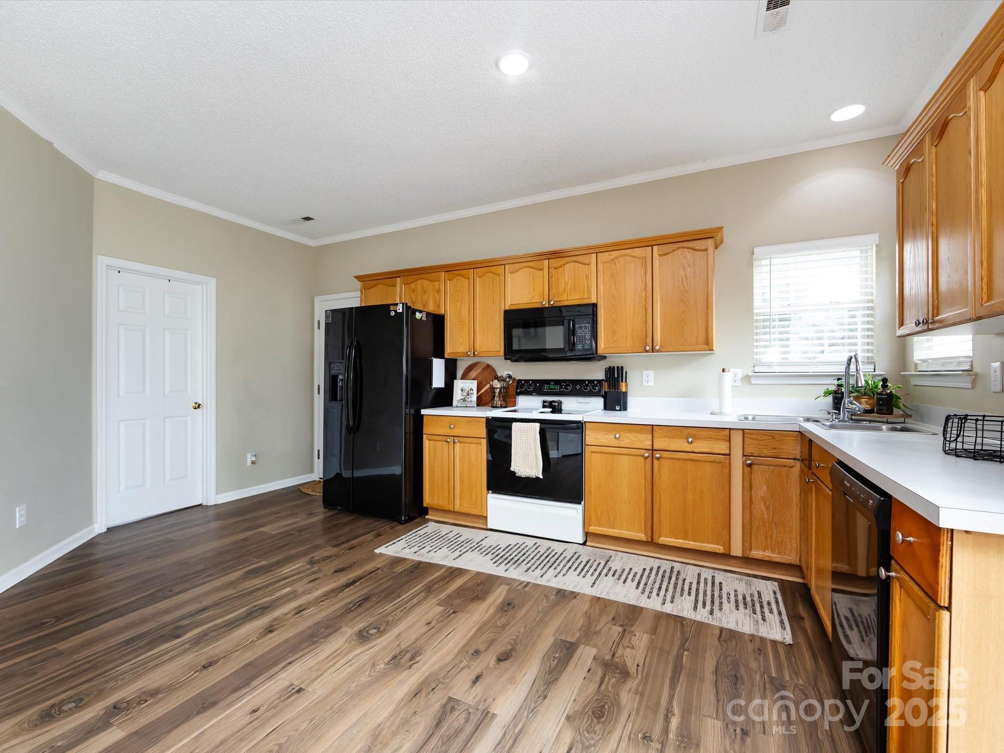 3910 Faith Church Road Indian Trail, NC 28079 - Photo 18 of 47 a kitchen with stainless steel appliances wooden floors and wooden cabinets