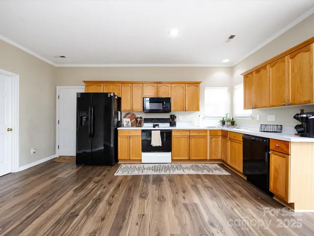 a kitchen with stainless steel appliances granite countertop wooden cabinets a stove top oven a sink and dishwasher with wooden floor