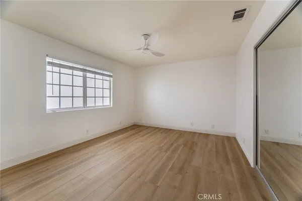 an empty room with wooden floor ceiling fan and windows