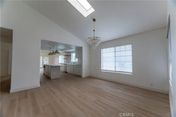 an empty room with wooden floor chandelier and windows