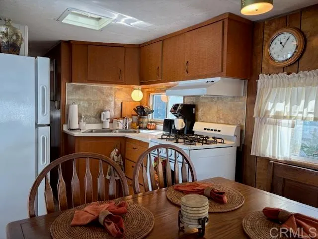 a kitchen with stainless steel appliances granite countertop a refrigerator a stove a sink and a dining table with garden view