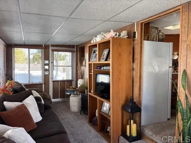 a living room with furniture a large window a flat screen tv and a refrigerator