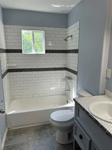 a bathroom with a granite countertop toilet and a bathtub