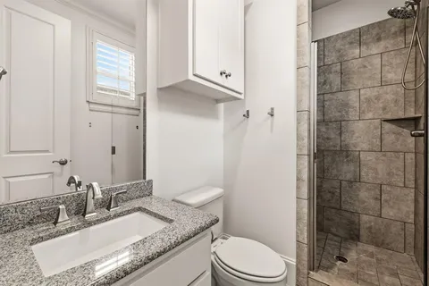 a bathroom with a granite countertop sink toilet a mirror and shower