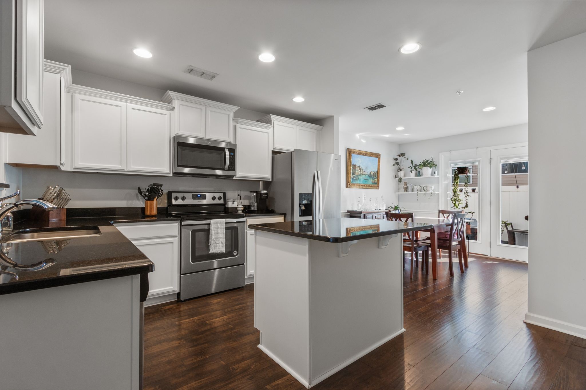 1002 Muna Court Spring Hill, TN 37174 - Photo 5 of 28 a kitchen with granite countertop a refrigerator stove a sink a dining table and chairs with wooden floor