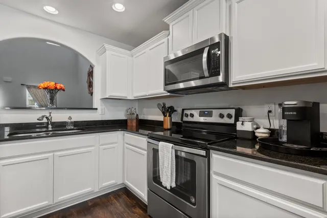 a kitchen with stainless steel appliances granite countertop grey cabinets a stove a sink and dishwasher