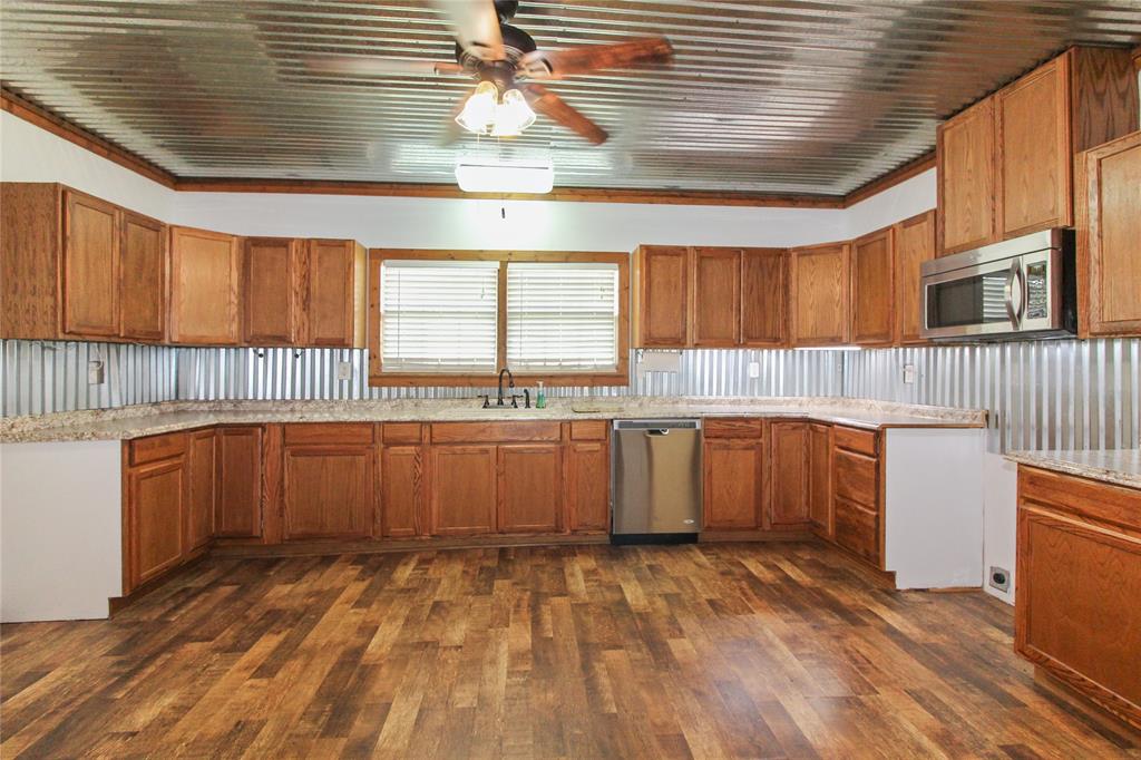 455 Hughes Cemetery Road Italy, TX 76651 - Photo 26 of 40 a kitchen with stainless steel appliances granite countertop a sink and wooden cabinets