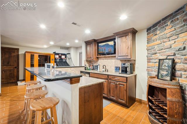 13665 Random Ridge View Colorado Springs, CO 80921 - Photo 37 of 49 Kitchen with tasteful backsplash, dishwasher, light hardwood / wood-style floors, dark stone countertops, and a breakfast bar area