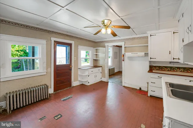 a kitchen that has a lot of cabinets a sink appliances and wooden floor