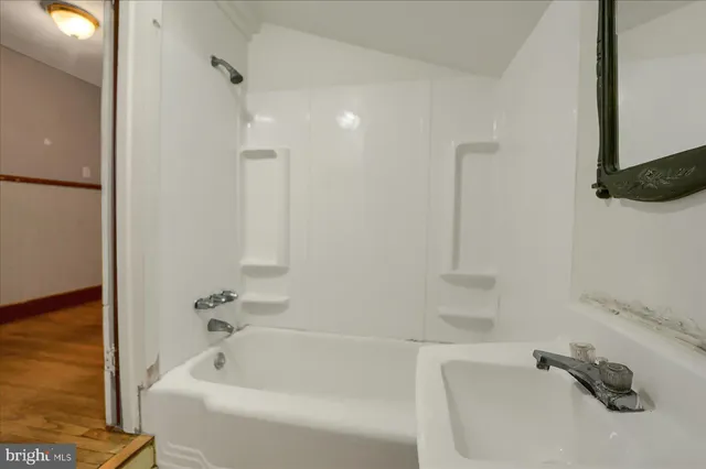 a white bath tub sitting next to a white sink and vanity