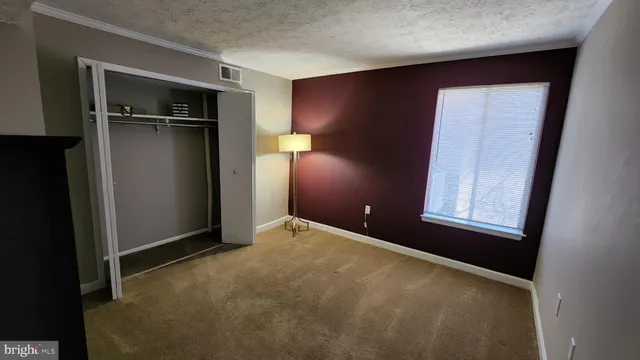 a view of an empty room with closet and a window