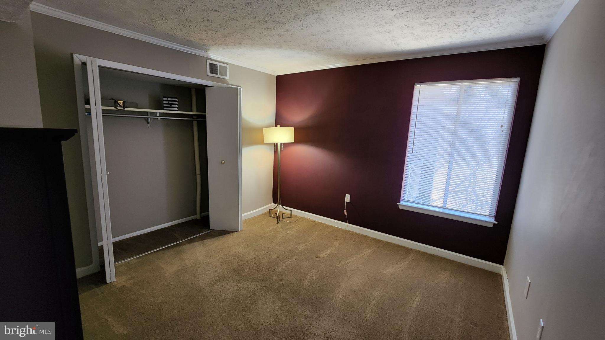 a view of an empty room with closet and a window