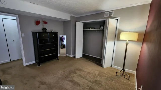 a view of an empty room with closet and mirror