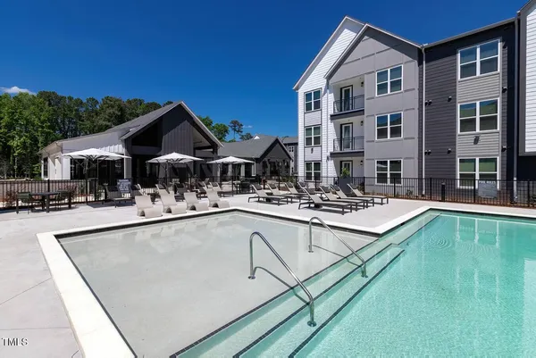 a view of swimming pool with outdoor seating and house in the background