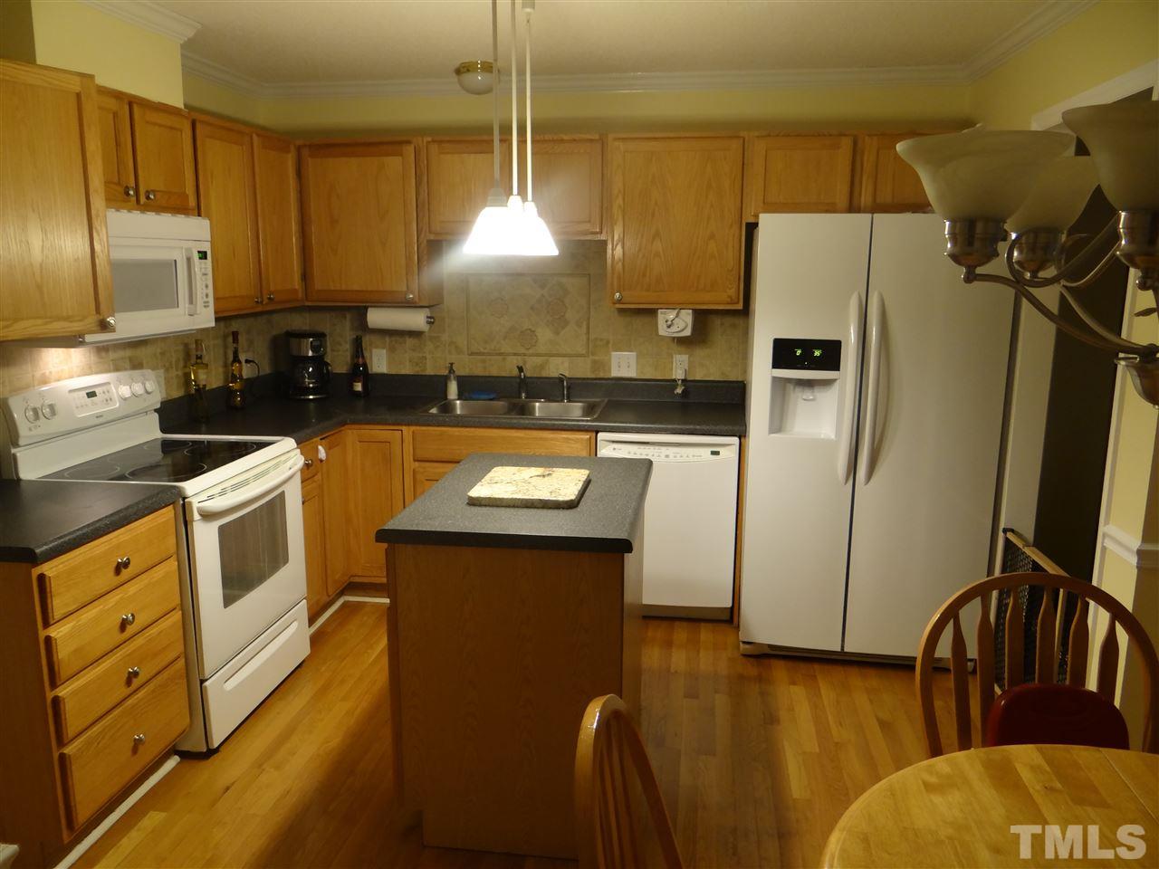 4208 Wolftrap Road Raleigh, NC 27616 - Photo 7 of 23 a kitchen with stainless steel appliances a stove a refrigerator a sink a stove and white cabinets with wooden floor