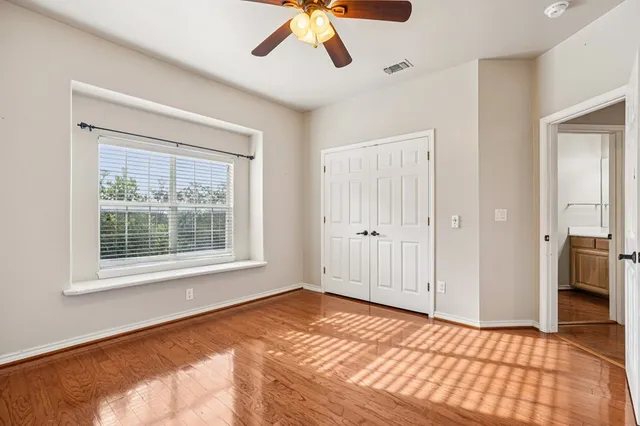 a view of an empty room with window and a chandelier fan