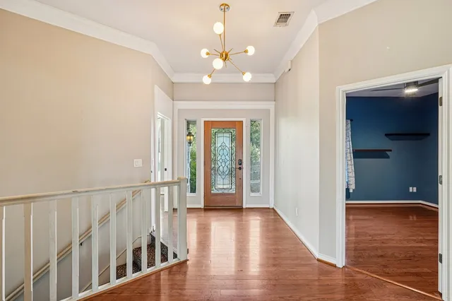 a view of a hallway with wooden floor and a chandelier