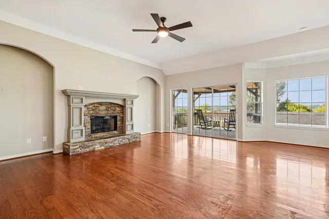 an empty room with floor to ceiling windows and fireplace