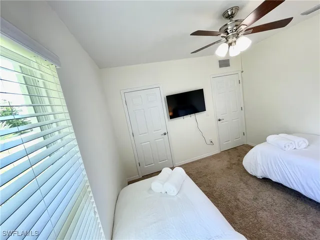 a bedroom with a bed and a flat tv screen on dresser