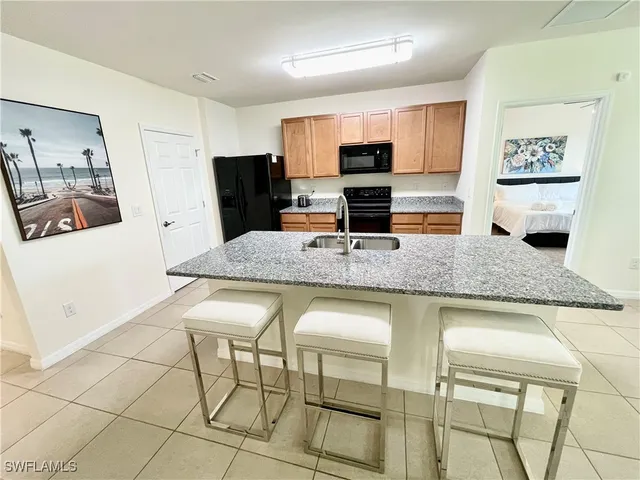 a kitchen with granite countertop a table chairs microwave and sink