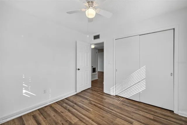 a view of a hallway with wooden floor and a ceiling fan