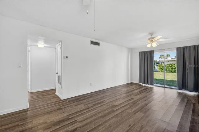 a view of an empty room with a window and wooden floor