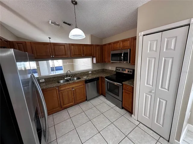 a kitchen with stainless steel appliances granite countertop a stove a sink and a refrigerator