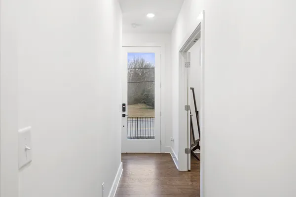 a view of a hallway with wooden floor and a bathroom