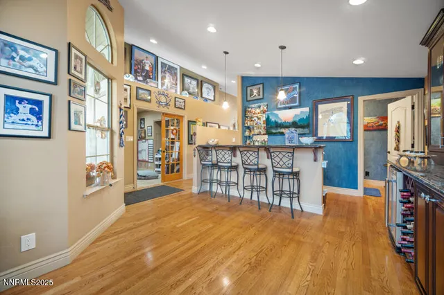 a open kitchen with stainless steel appliances granite countertop a refrigerator a stove top oven a dining table and chairs with wooden floor