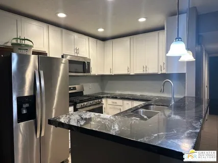 a kitchen with stainless steel appliances granite countertop a sink a stove and a refrigerator