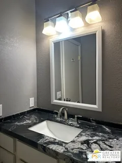 a bathroom with a granite countertop sink and a mirror