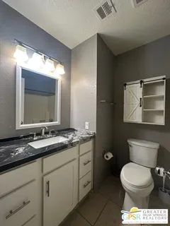 a bathroom with a granite countertop toilet sink and mirror