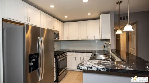a kitchen with kitchen island granite countertop a sink cabinets and stainless steel appliances