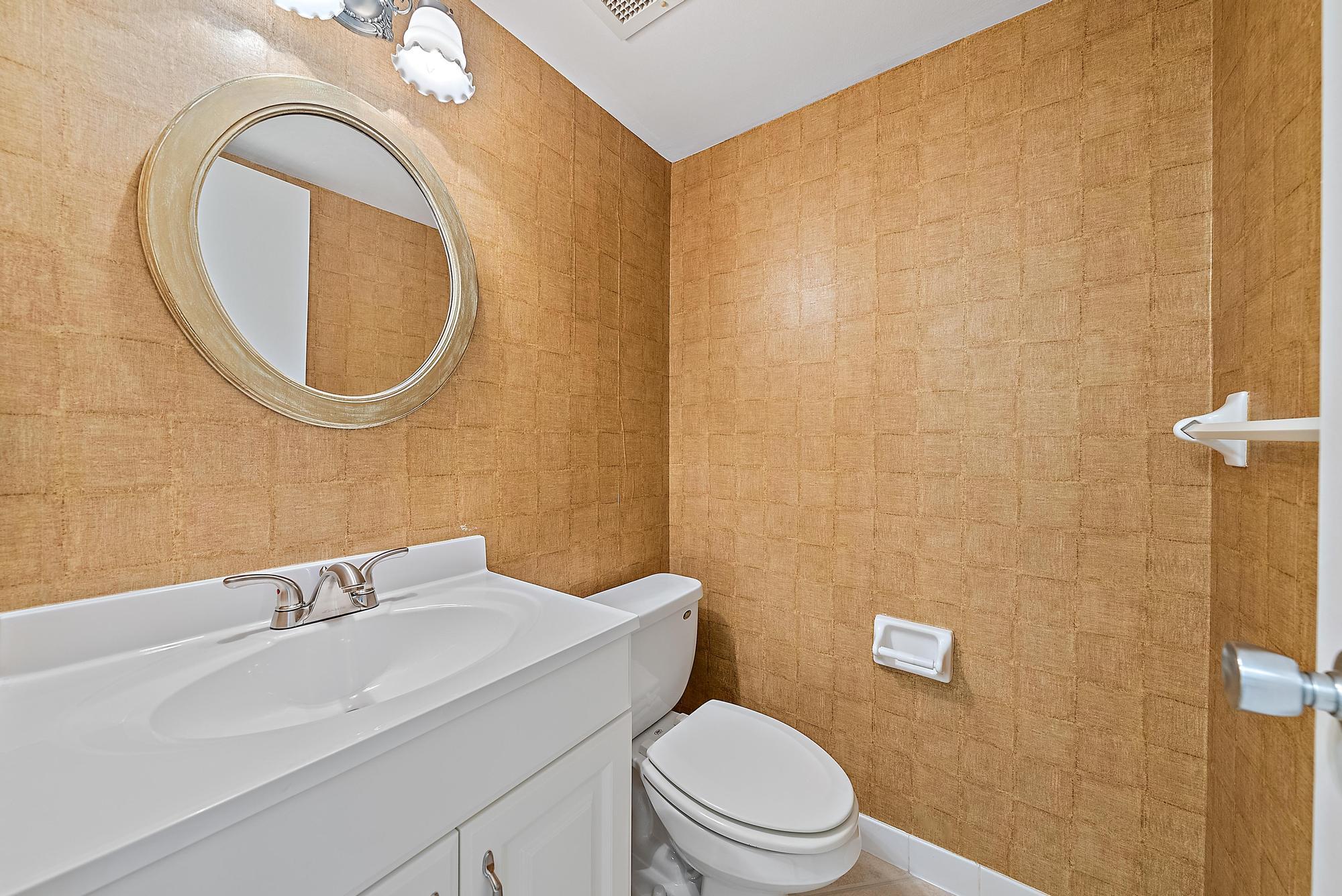 1208 Marine Way, Unit 105 North Palm Beach, FL 33408 - Photo 12 of 22 a bathroom with a toilet a sink and mirror