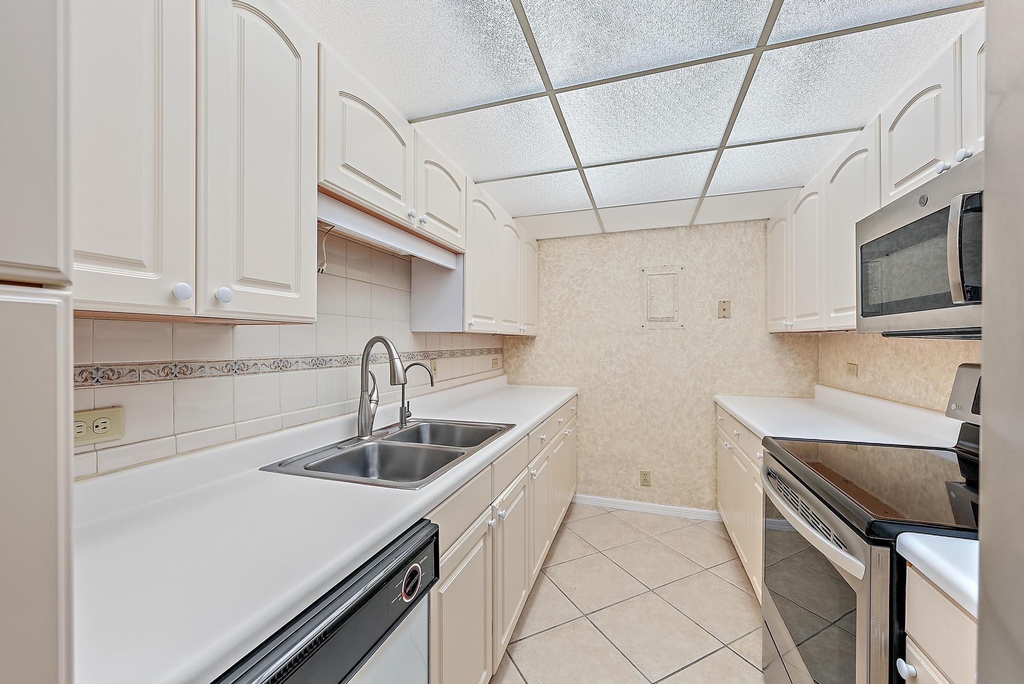 1208 Marine Way, Unit 105 North Palm Beach, FL 33408 - Photo 5 of 22 a kitchen with stainless steel appliances a sink stove and cabinets