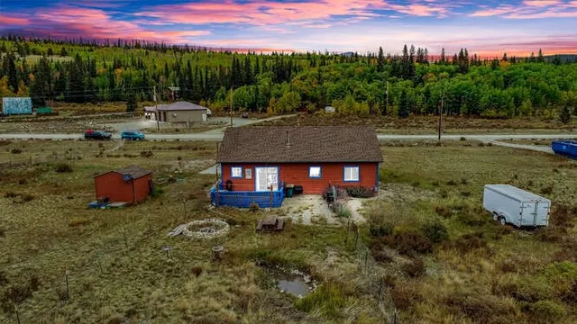 a view of a house with a yard and a car park in the background