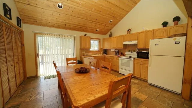 a kitchen with a refrigerator a stove a sink and a dining table with wooden floor